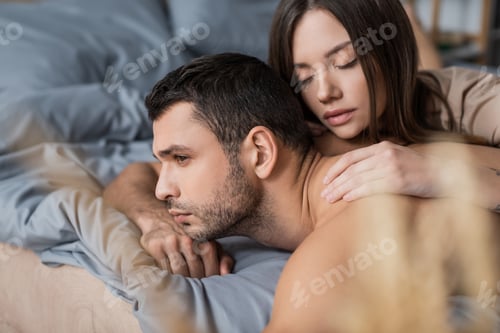 Preview: Brunette woman with closed eyes touching muscular man on blurred bed