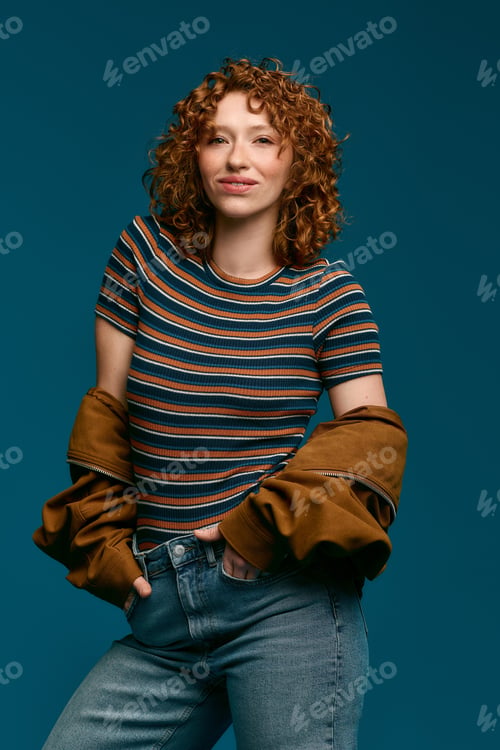 Preview: Stylish young woman poses confidently in trendy outfit against vibrant blue backdrop