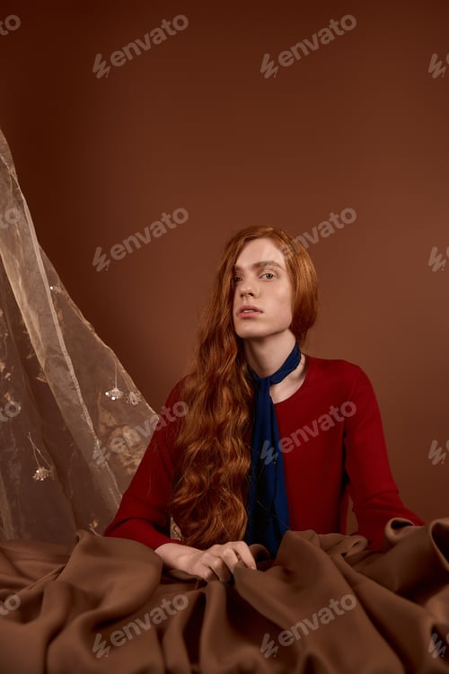 Preview: Handsome young man in elegant attire exudes charm with long red hair and a captivating gaze
