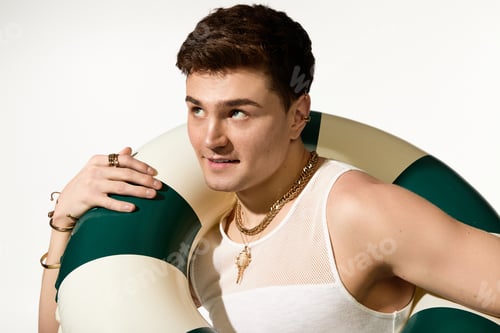 Preview: Stylish young man with a pool float enjoying the vibrant summer season in a cheerful setting