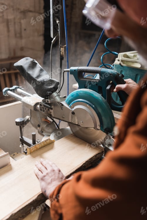 Preview: Partial View of Blurred Woodworker Cutting Board With Miter Saw