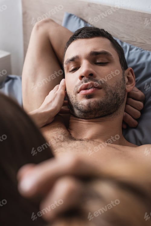 Preview: Sensual man touching blurred girlfriend while lying on bed at home