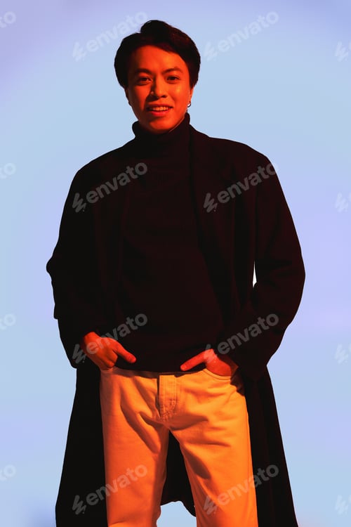 Preview: Stylish young man presents unique fashion choices in a vibrant studio setting