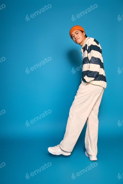 Preview: Stylish young man in a vibrant studio demonstrating unique fashion choices