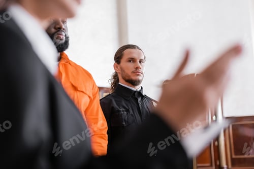 Preview: Bailiff Looking at Blurred Prosecutor While Standing Near Accused African Amrican Man in Court