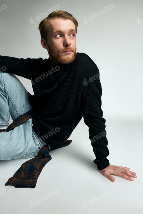 Preview: Stylish young man poses confidently in a modern studio setting, showcasing contemporary fashion