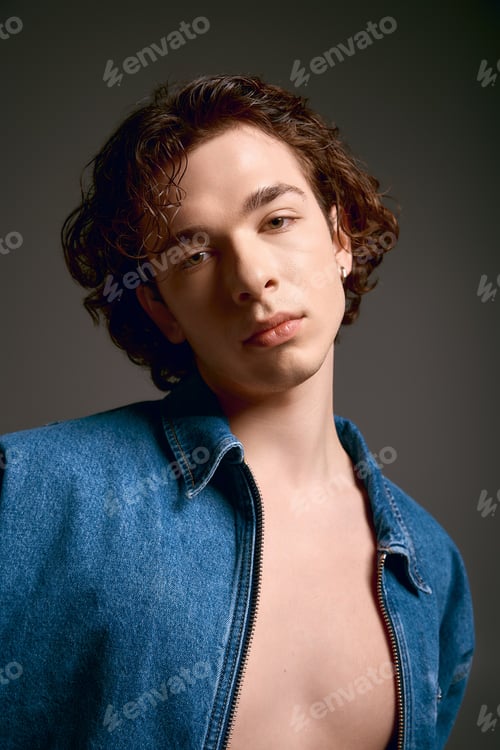Preview: Handsome young man with curly hair expresses deep emotions in stylish denim attire