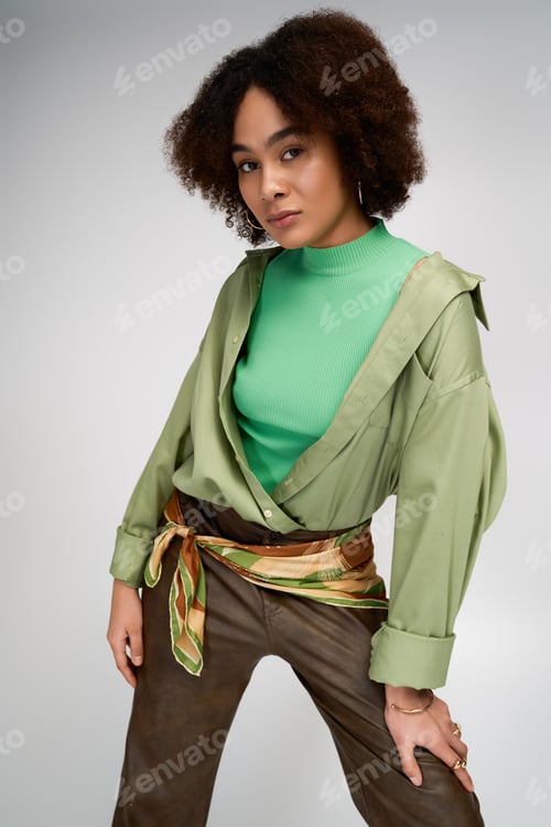 Preview: Young woman showcases stylish green attire and confident pose in modern setting