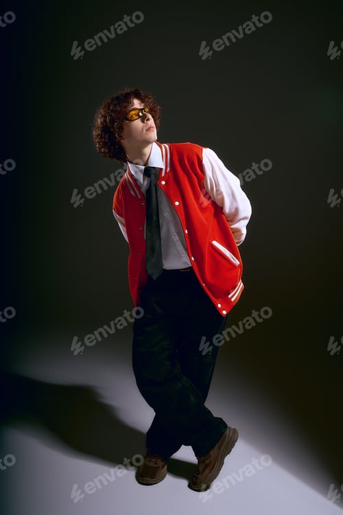Vista previa: Handsome young man expresses strong emotions in stylish outfit against a dark backdrop
