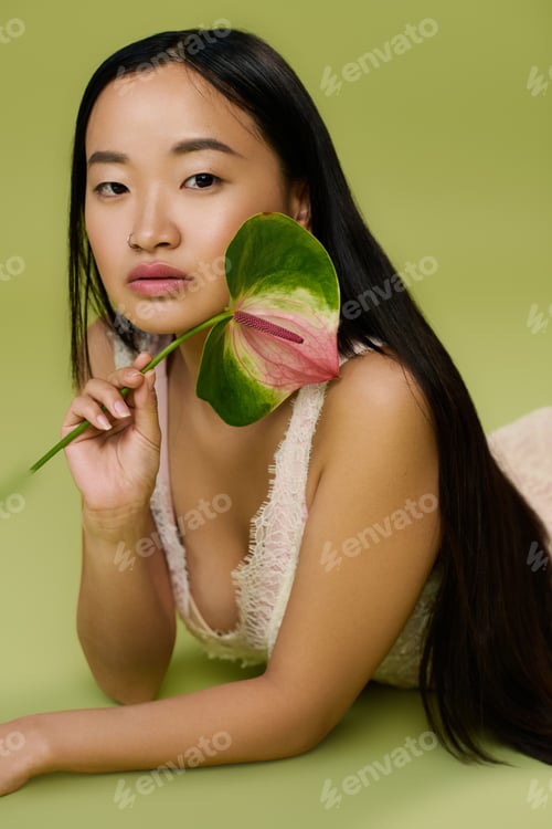 Preview: Elegant young woman in summer attire radiates charm in a tranquil studio setting