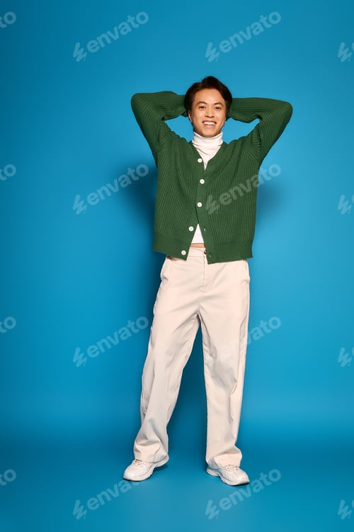 Preview: Stylish young man radiates confidence in vibrant studio setting with trendy outfit