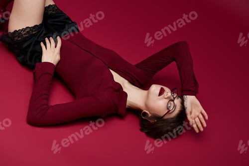 Preview: Fashionable young woman rests stylishly on a vibrant crimson backdrop