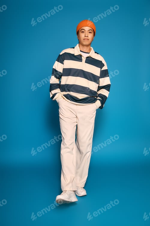 Preview: Stylish young man showcases modern fashion in a vibrant studio setting