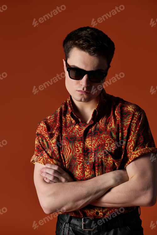 Preview: Confident young man showcasing style with a bold shirt and shades against a vibrant backdrop