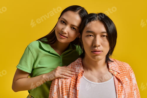 Preview: Young couple sharing a joyful moment in trendy outfits against a vibrant yellow backdrop