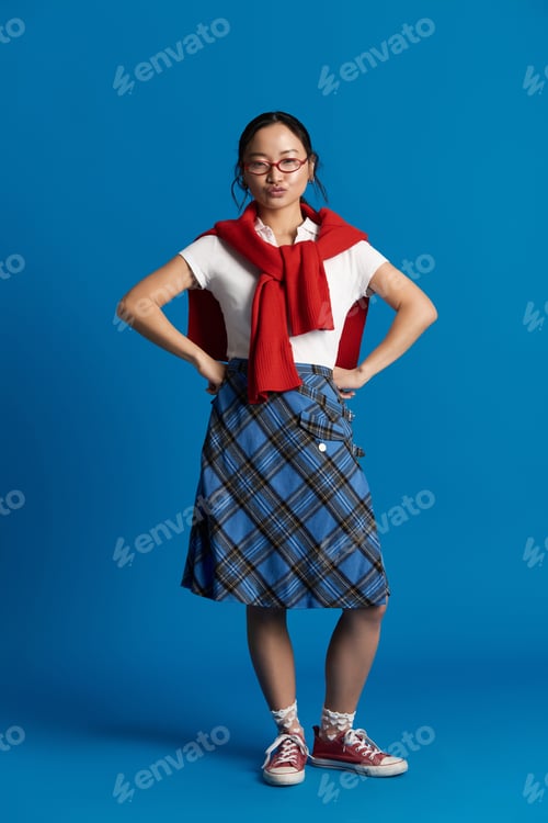 Preview: Stylish young asian woman showcases modern fashion with confidence against a vibrant blue backdrop