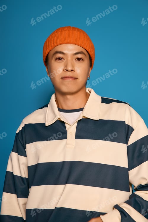 Preview: Stylish young asian man showcases unique fashion sense in vibrant studio setting