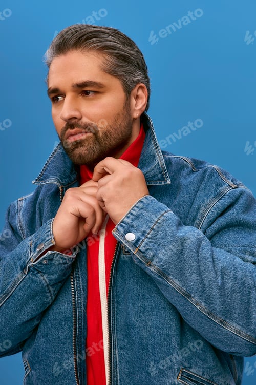 Preview: Stylish man in denim jacket poses confidently against a vibrant blue background