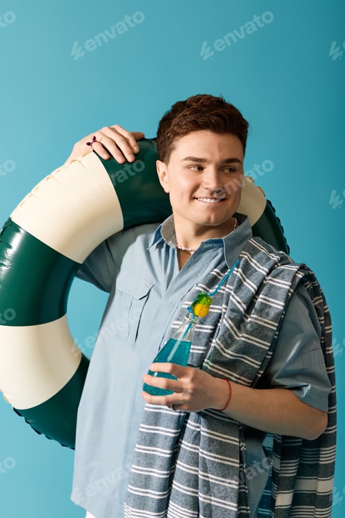 Preview: Stylish young man enjoys summer vibes with a lifebuoy and refreshing drink