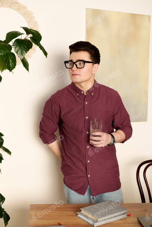 Preview: Charming young man enjoying a moment in a stylish room with plants and books