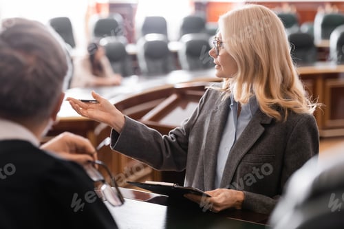 Preview: Middle Aged Attorney Pointing With Hand Near Grey-haired Judge in Courtroom