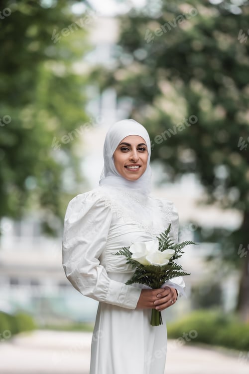 Preview: Smiling Muslim Bride With Diamond Ring on Finger Holding Wedding Bouquet