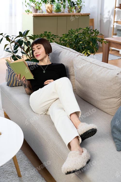 Preview: Relaxing at home with a book in hand on a cozy afternoon amidst house plants
