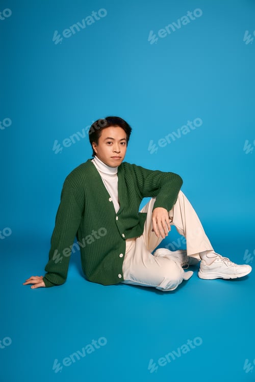 Preview: Stylish asian young man showcasing modern fashion in a vibrant studio setting