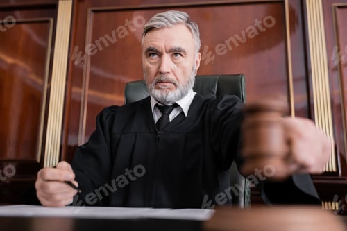 Preview: Senior Judge in Mantle Holding Blurred Gavel While Sentencing in Court