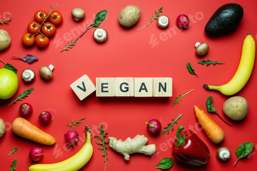 Preview: Flay lay with vegan lettering on wooden cubes near ripe vegetables and fruits on red background