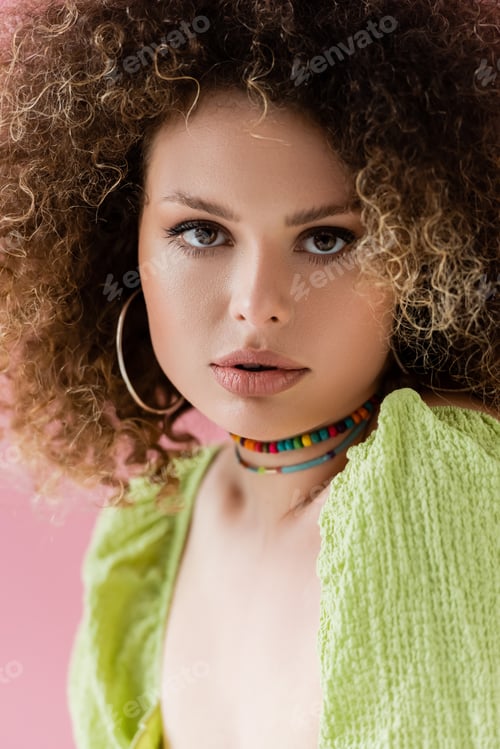 Preview: Portrait of curly model in green blouse isolated on pink