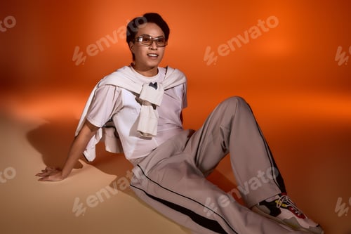Preview: Stylish young man showcases modern fashion in vibrant studio setting