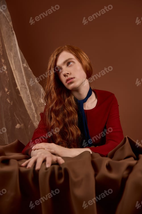 Preview: Handsome young man with long red hair embodies elegance in stylish attire on a rich backdrop