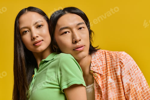 Preview: Young couple sharing joy and warmth in vibrant fashion against a bright yellow backdrop
