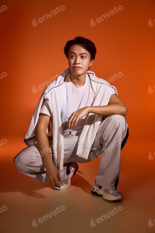 Preview: Stylish asian young man highlights unique fashion choices in vibrant studio atmosphere