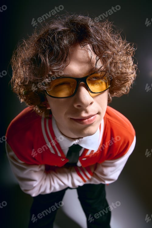 Preview: Emotional expression of a young man in stylish attire with curly hair and trendy glasses