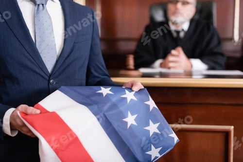 Preview: Lawyer in Suit Holding Usa Flag in Courtroom Near Senior Judge on Blurred Background