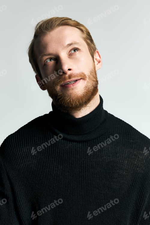Preview: Handsome stylish man in black turtleneck with a thoughtful gaze in a minimalist setting