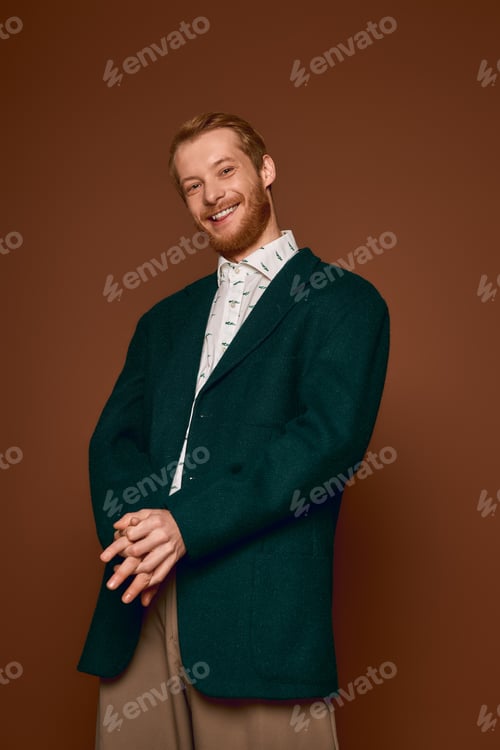 Preview: Charming red haired man exudes confidence in stylish attire against a warm backdrop