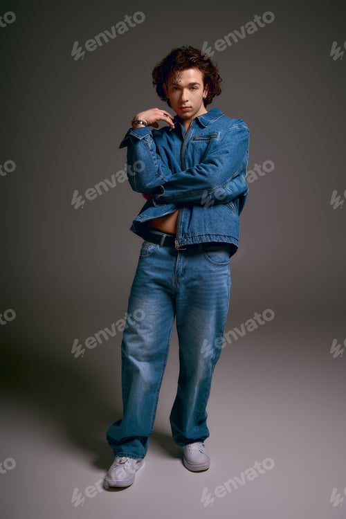Preview: Emotional young man with curly hair showcases stylish denim fashion in a modern setting