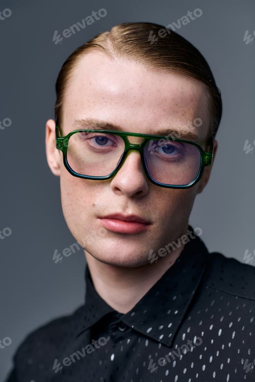 Preview: Stylish young man showcases modern fashion in a studio setting with trendy glasses
