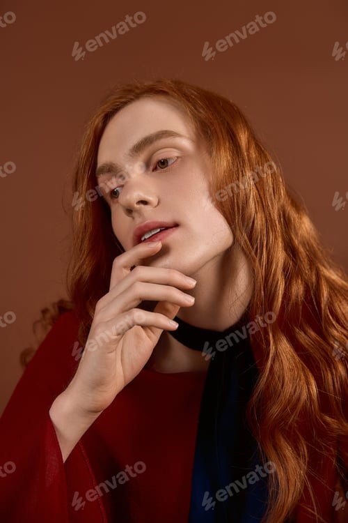 Preview: Handsome young man with long red hair showcases elegant fashion in a striking pose