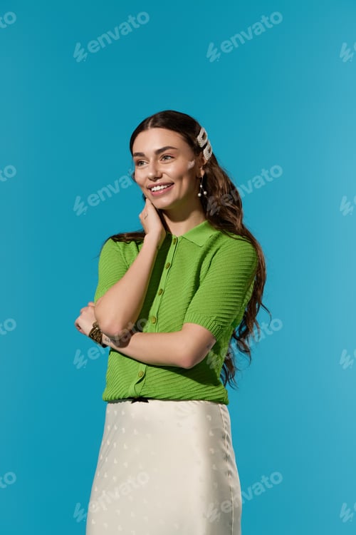 Preview: Charming stylish woman in vibrant green attire poses against a bright blue backdrop