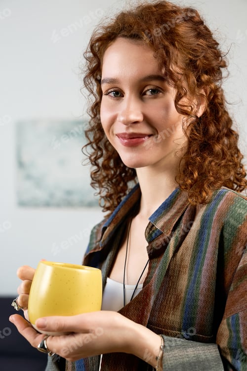 Preview: Beautiful woman enjoys her handmade hobby while sipping a warm drink in cozy surroundings