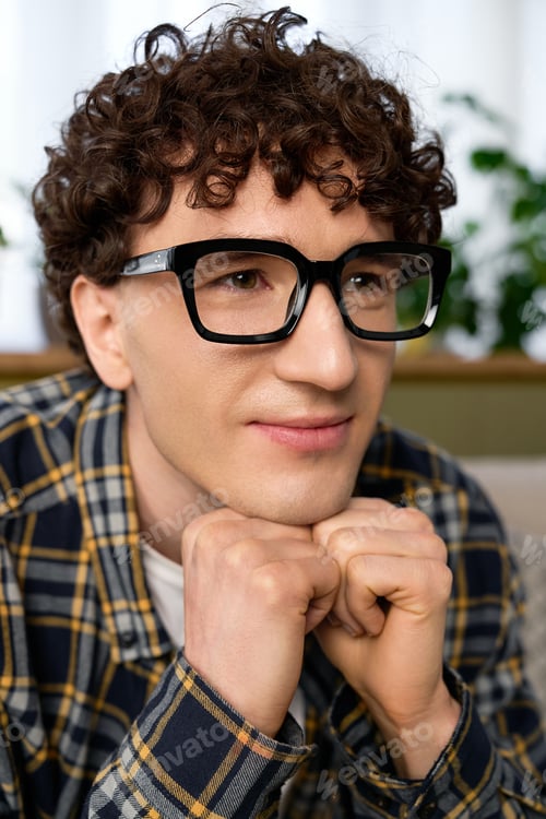 Preview: Young man in a modern apartment enjoying a peaceful moment with thoughtful expression