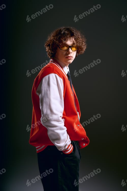 Preview: Emotional young man in stylish outfit conveys deep feelings amidst dramatic lighting