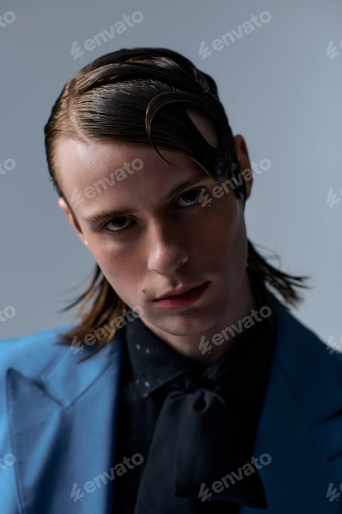 Preview: Young man's captivating charm in stylish outfit captured in a modern studio setting