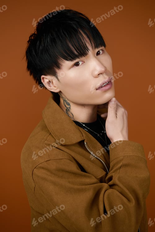 Preview: Young handsome man posing with confidence against a warm orange backdrop in a casual style