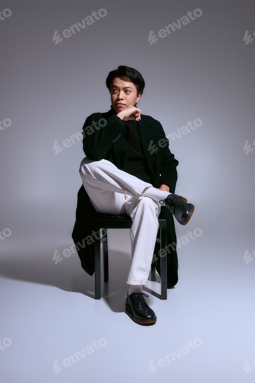 Preview: Stylish asian young man expressing personal fashion in a modern studio setting
