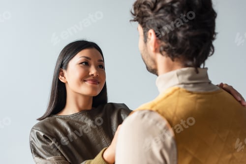 Preview: Pretty Asian Woman Smiling at Blurred Man Isolated on Grey